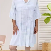 Robe large évasée à motifs, blanc, col mao, patte de boutonnage, volants aux manches et à la base, coupe fluide et élégante. Taille unique 36 au 40/42 vue devant
