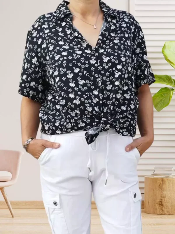 chemise-a-fleurs-noir-dv Chemise à fleurs manches courtes, coupe fluide et fermeture par boutonnage, look élégant et polyvalent, vue de face, nouée à la taille, coloris : noir.