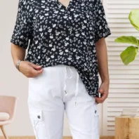 Chemise à fleurs manches courtes, coupe fluide et fermeture par boutonnage, look élégant et polyvalent, vue de face, rentrée dans la bas, coloris : noir.