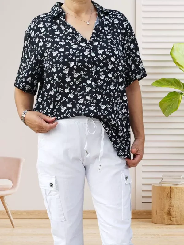 chemise-a-fleurs-noir-dv1 Chemise à fleurs manches courtes, coupe fluide et fermeture par boutonnage, look élégant et polyvalent, vue de face, rentrée dans la bas, coloris : noir.