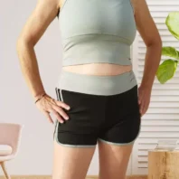 Ensemble de sport respirant avec brassière sans manches et short bicolore fluide avec large élastique à la taille, vert et noir, vue devant
